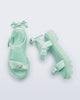 Side and top view of a pair of green Town Bow sandals with bows and a pearl in the center of each bow