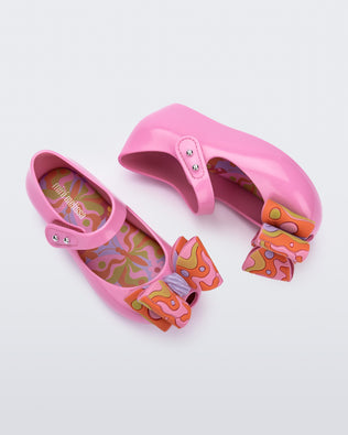 Top and side view of a pair of pink with multi-colored patterned bow Ultragirl Wonderland baby flats