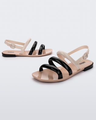 Angled view of a pair of black and beigeEssential Wave women's sandal with adjustable buckle.