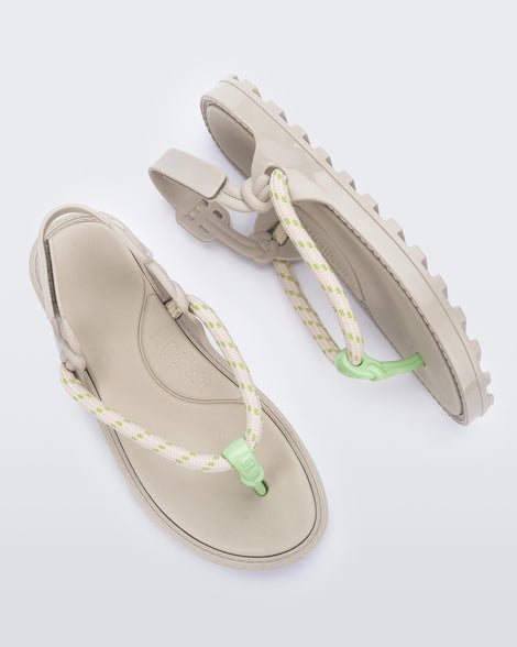 Top and side view of a pair of beige Bond sandals with textile strap and green toe piece