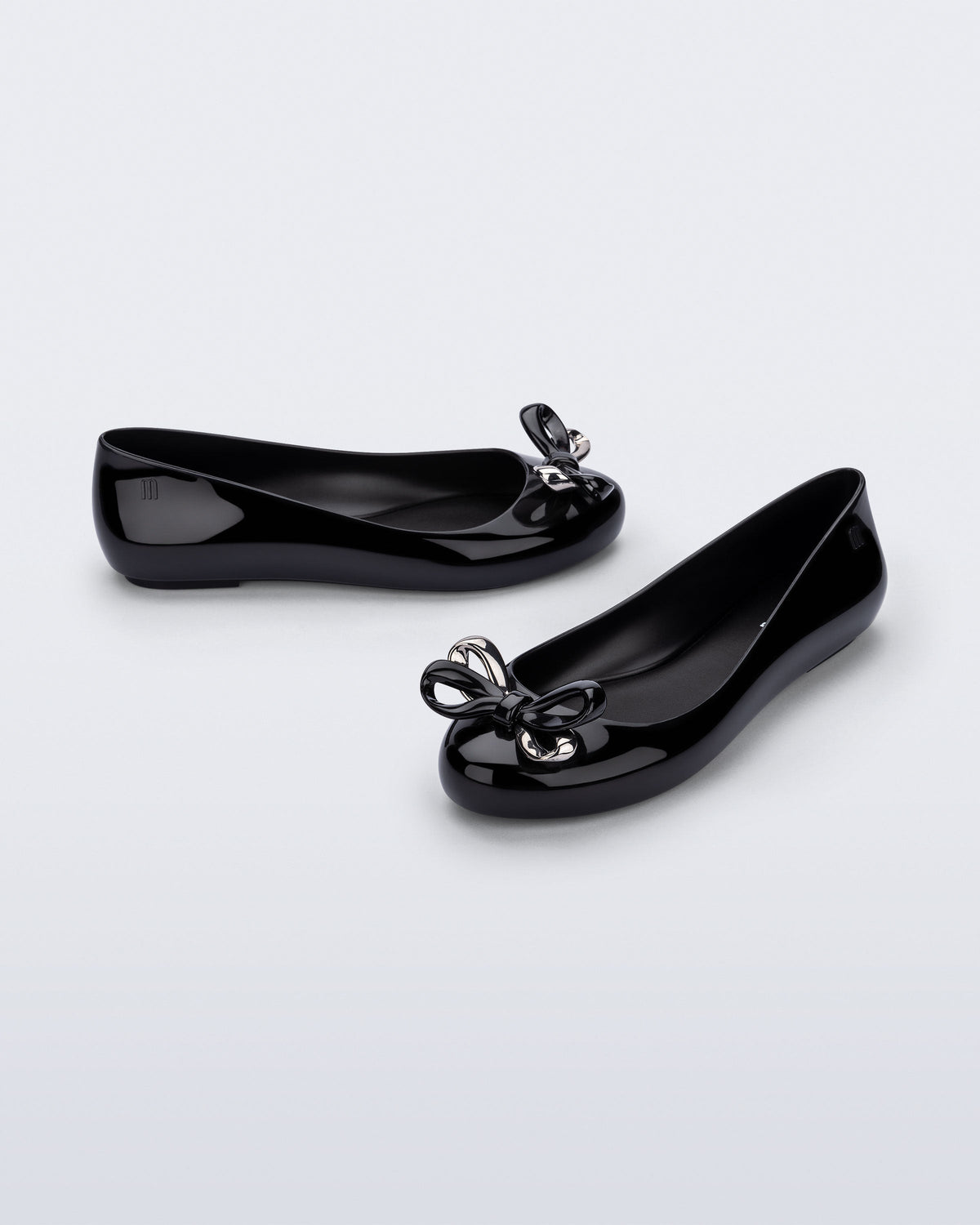 Side and angled view of a pair of black Sweet Love Glam ballerina flats with chrome bow
