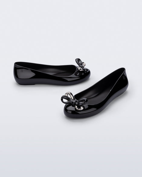 Side and angled view of a pair of black Sweet Love Glam ballerina flats with chrome bow