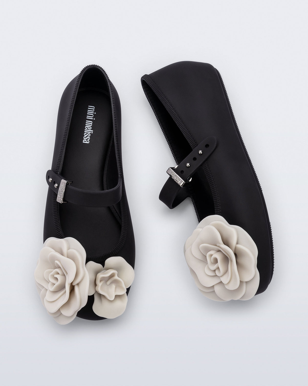 Side and top view of a pair of black Soft Ballerina Petals kids flat with beige flowers