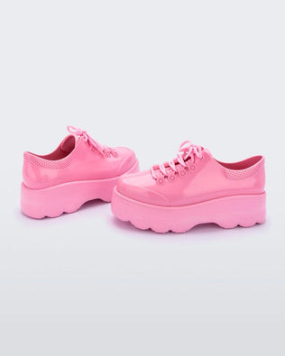 Side view of a pair of solid pink platform Melissa Kick Off Sneakers with laces.