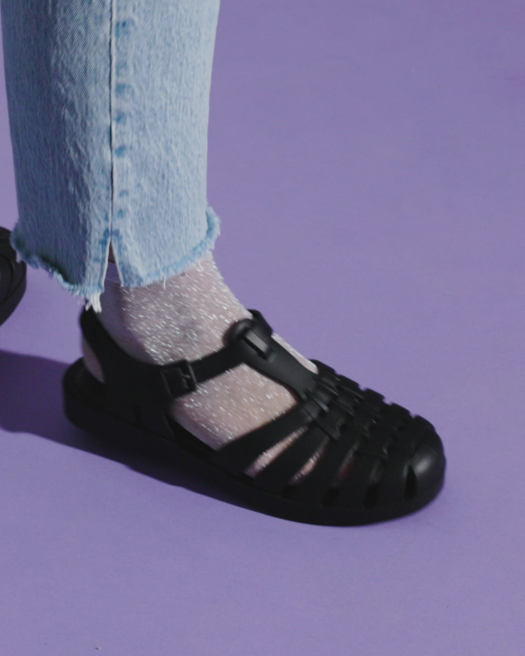 Video with no sound of a model in jeans wearing a pair of black Possession fisherman sandals with socks.