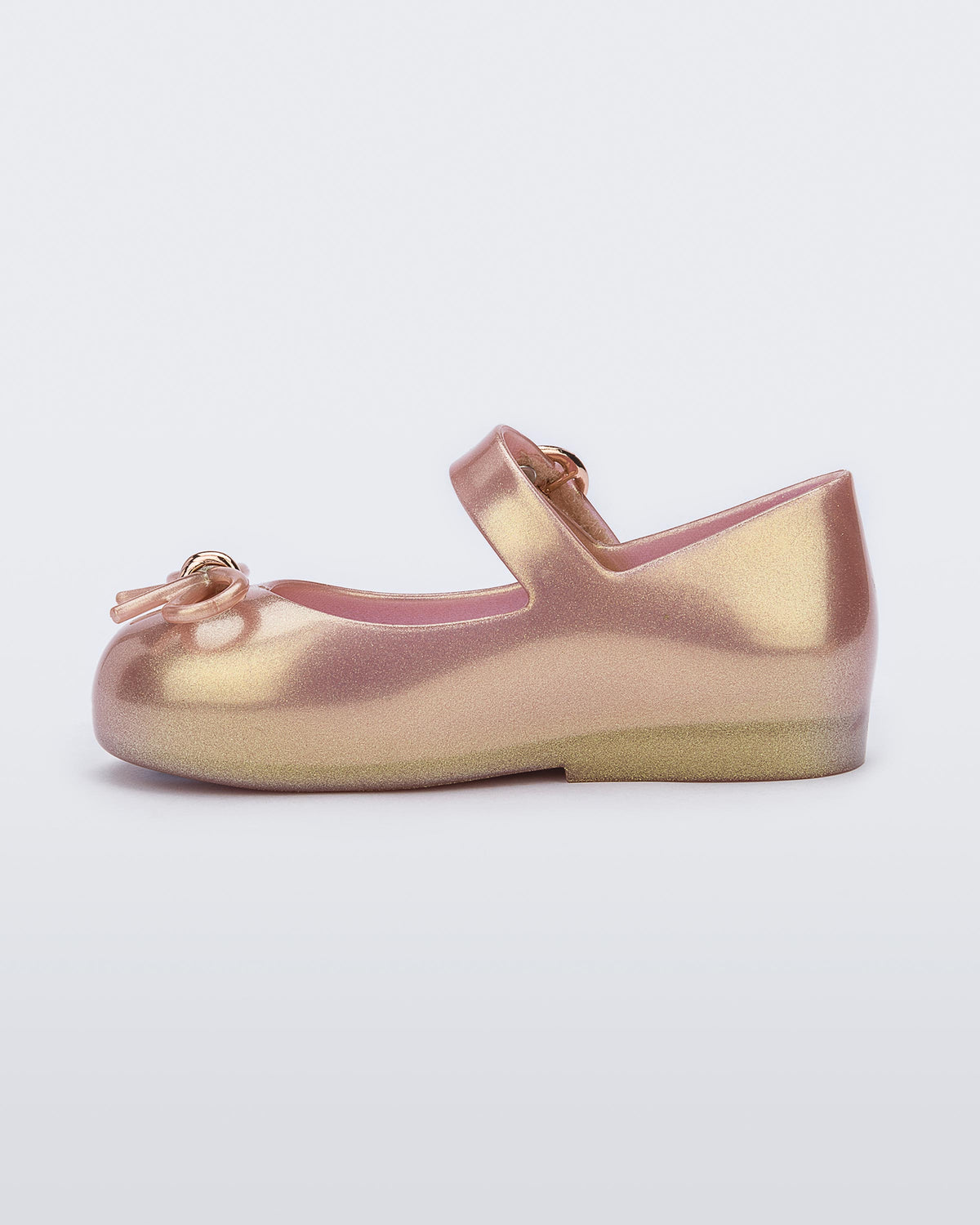 An inner side view of a pink Mini Melissa Sweet Love flat with a top strap and a bow detail on the toe.