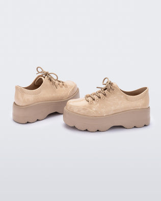 An angled side view of a pair of beige platform Melissa Kick Off Sneakers with laces.