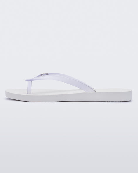 An inner side view of a white/clear Melissa Sun Venice flip flop with a white sole and clear straps with 