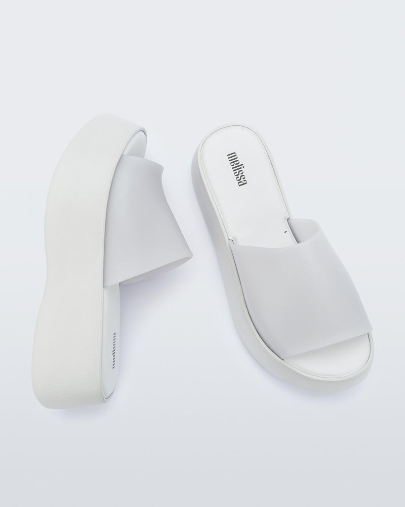 Top and angled view of a pair of white Melissa Becky platform slides. 