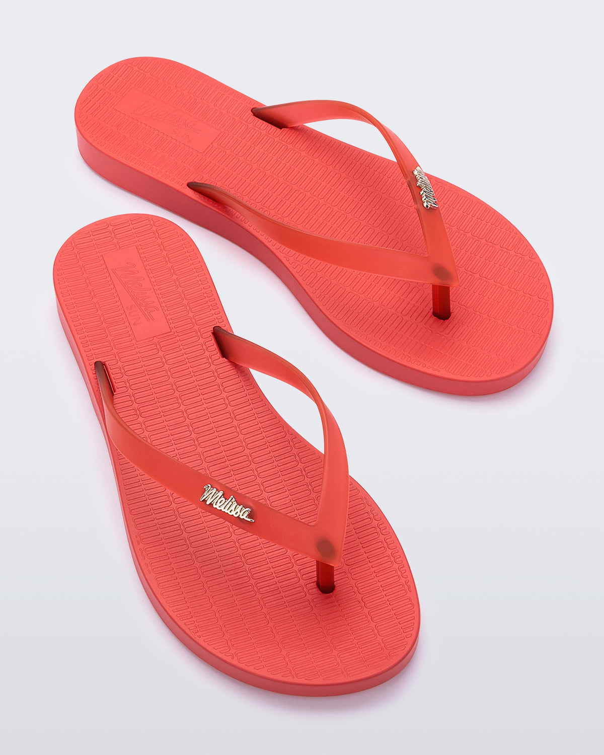 Top view of a pair of red Melissa Sun Venice flip flops with a "melissa" logo on the strap.