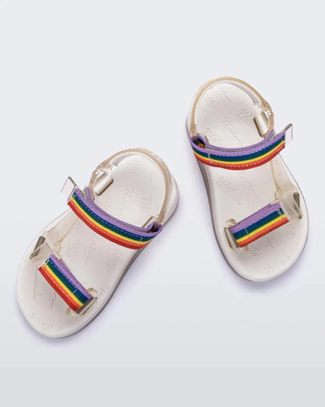 Top view of a pair of white Mini Melissa Papete sandals with rainbow straps .